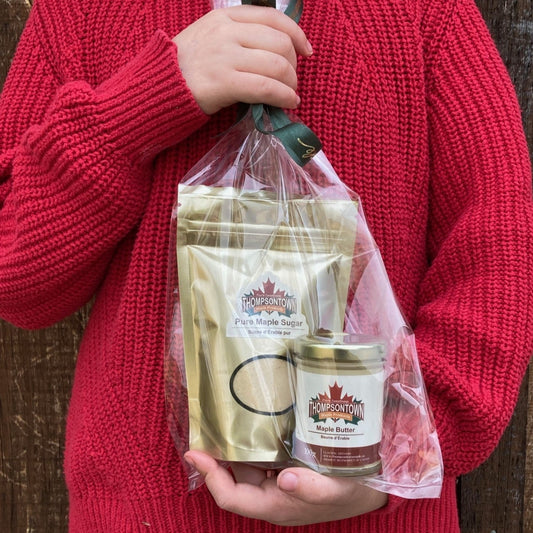 Small hands holding gift set containing maple butter and maple granulated sugar