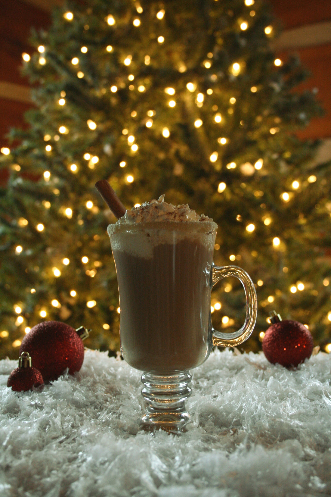 Maple syrup hot chocolate in from of a Christmas tree with white lights